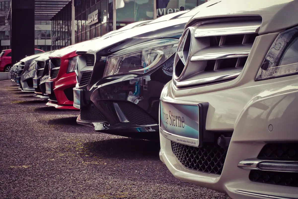 Row of dealer inventory parked outside a dealership building