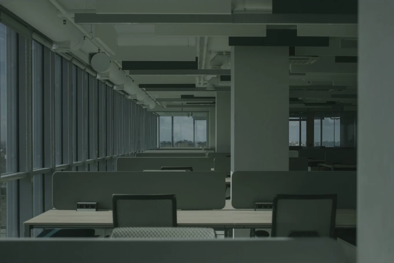 Unoccupied office space with desks and large windows